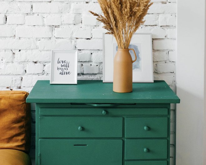 green chest of drawes with vase and picture frame